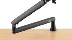 A black mic boom arm sits on a wooden table.